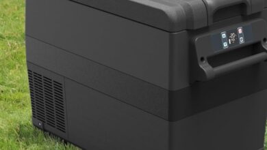 Alpicool NCF35 35L Kompressor Kühlbox in schwarz auf grüner Wiese mit Berglandschaft