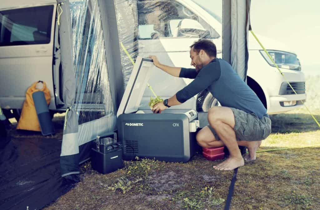 Mann befüllt Dometic CFX3 35 Kühlbox am Wohnmobil mit Vorzelt