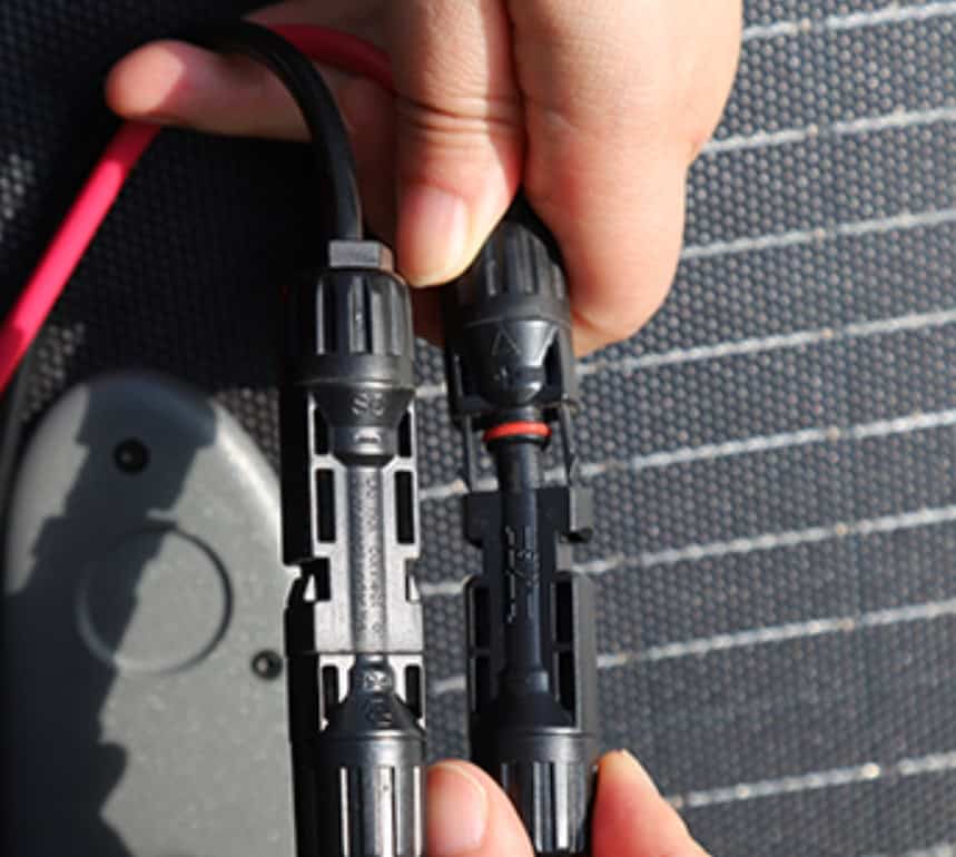 Hände halten MC4-Solarstecker vor Solarpanel-Hintergrund