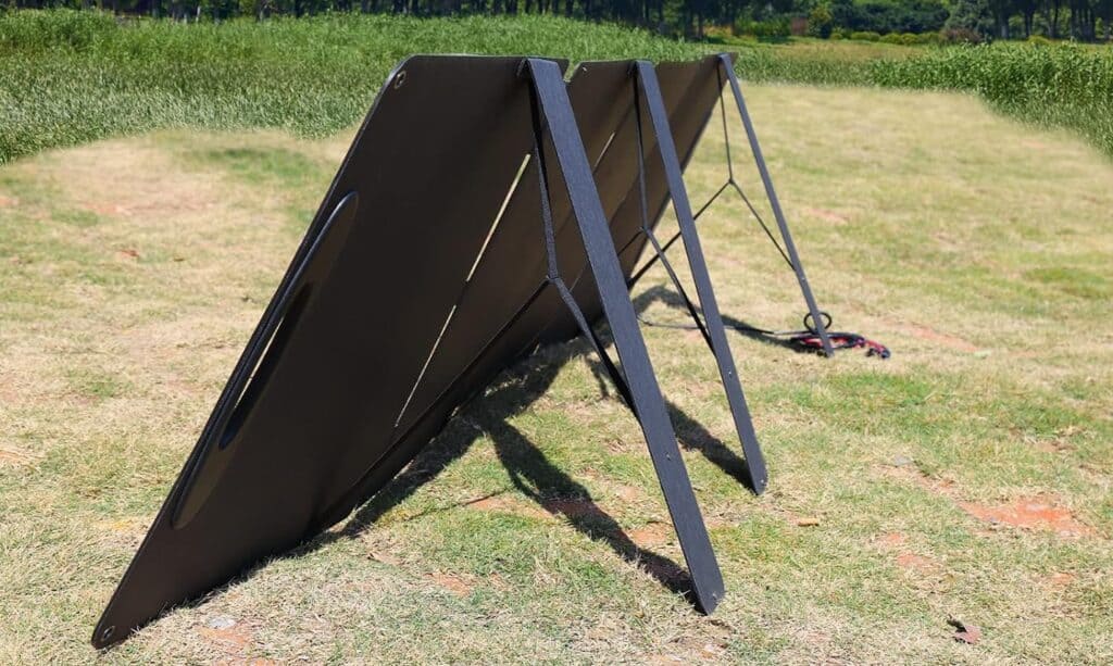 Zusammengefaltete schwarze Solarpanels gestapelt auf Wiese