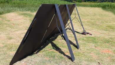 Zusammengefaltete schwarze Solarpanels gestapelt auf Wiese